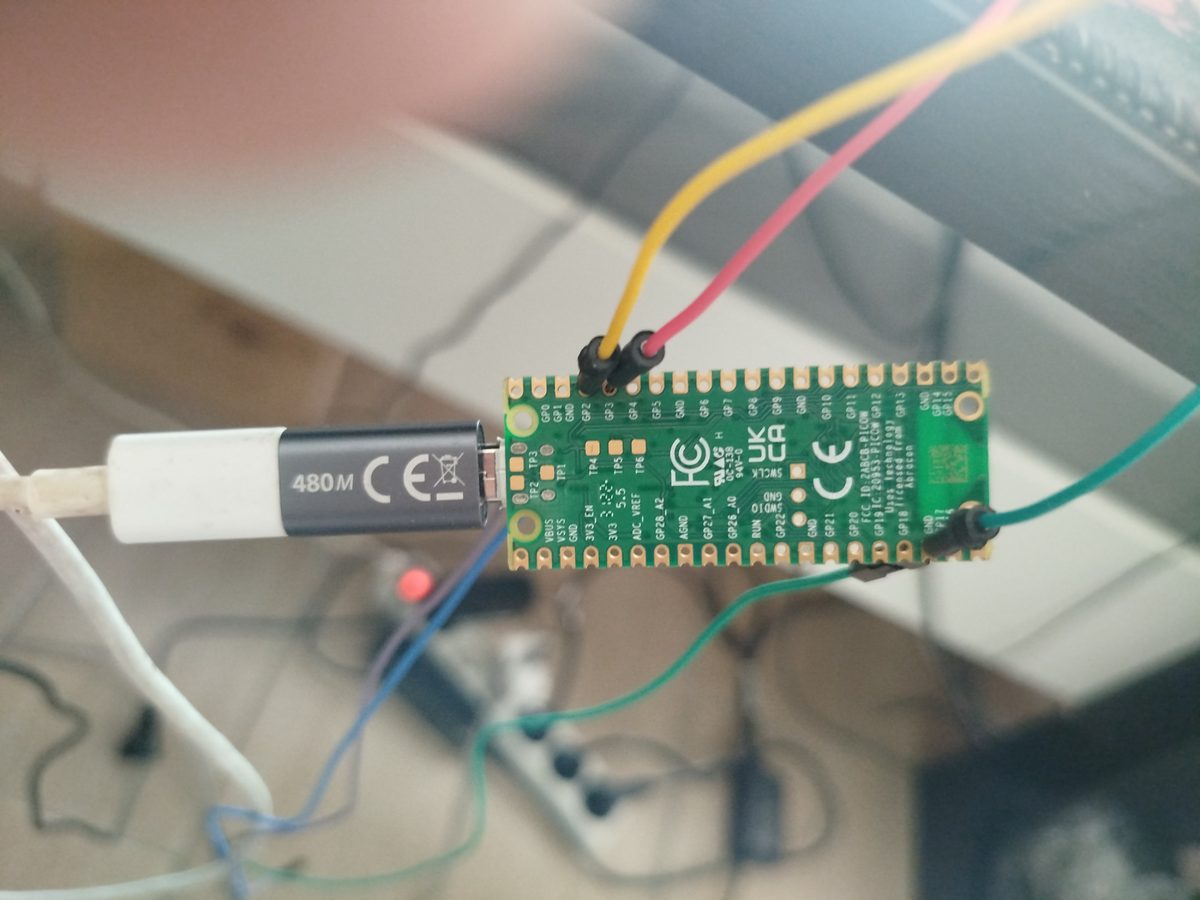 Raspberry Pi Pico W van onderen gezien, gevoed via USB, draden op GP2, GP3 en een massa